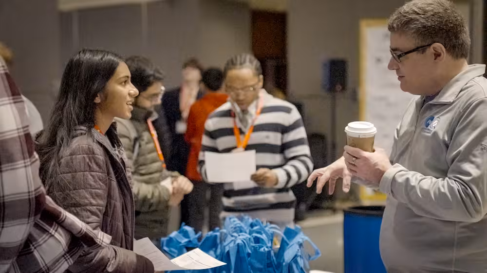 An image of a student talking to a sponsor at TechOlympics 2025: Inspire.